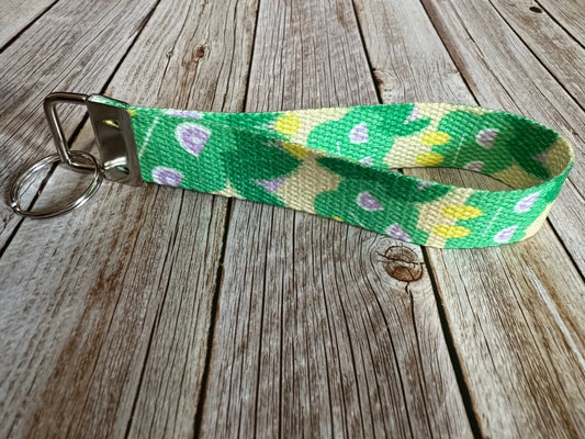 Keychain with a green and yellow pattern character on a wooden surface