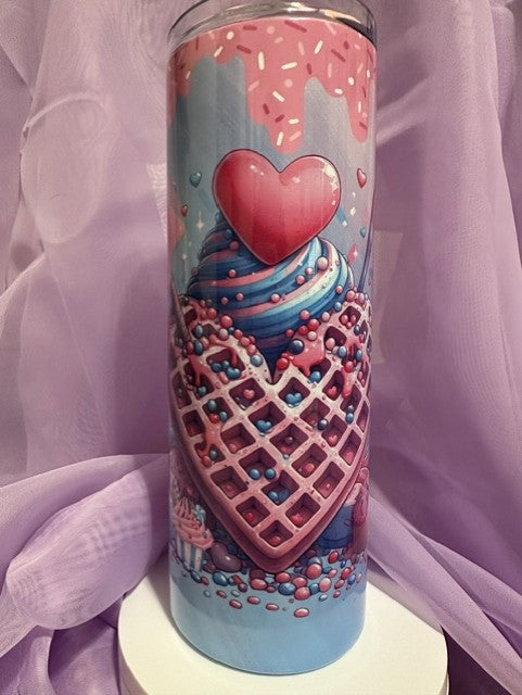 A tall, skinny tumbler decorated with an illustration of a heart-shaped waffle cone filled with blue and pink swirled ice cream, topped with a large red heart and sprinkles.