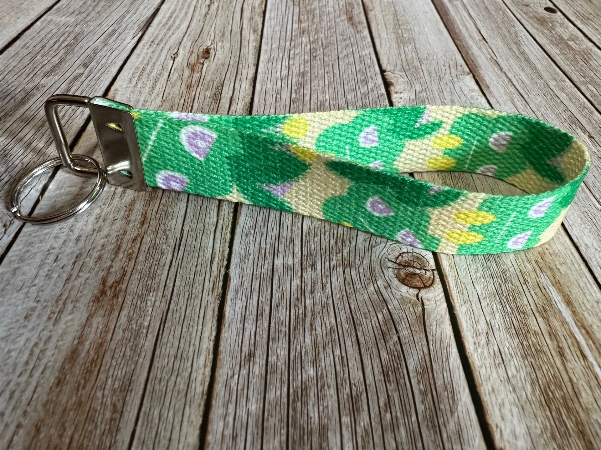 Keychain with a green and yellow pattern character on a wooden surface