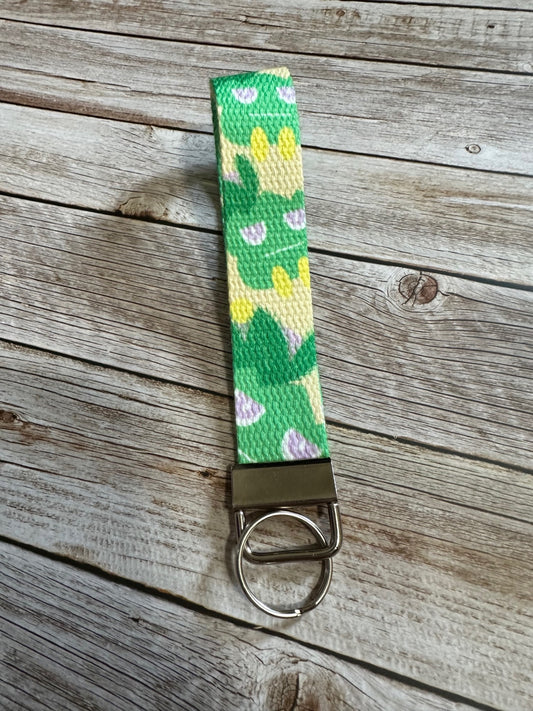 Keychain with a green and yellow pattern character on a wooden surface
