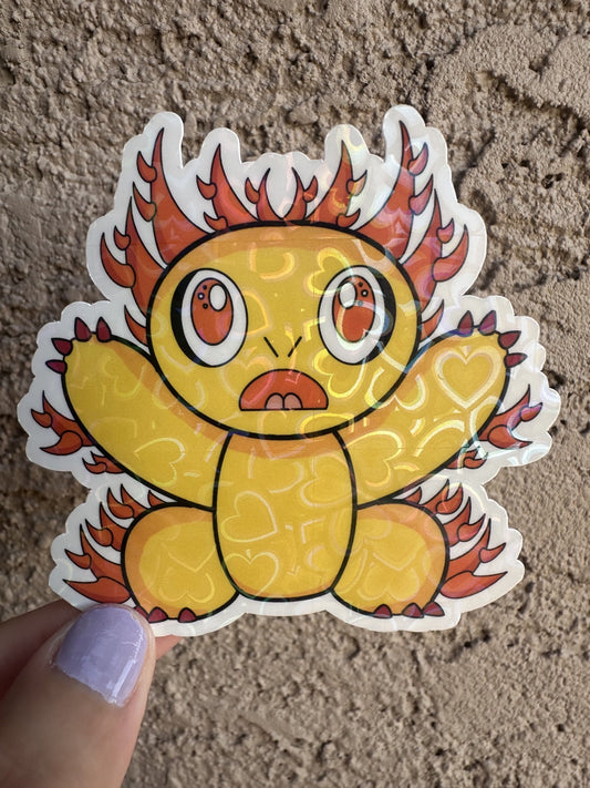 Fictional character heart holographic sticker that is yellow and has multiple spikes coming out of the character that are orange. The character has red nails with big orange eyes with white and black in them. 