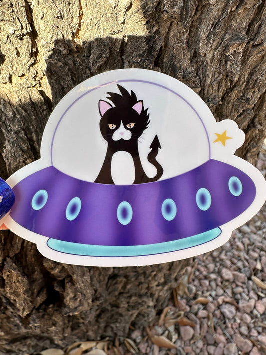 Sticker of a cat in a UFO against a tree bark background.