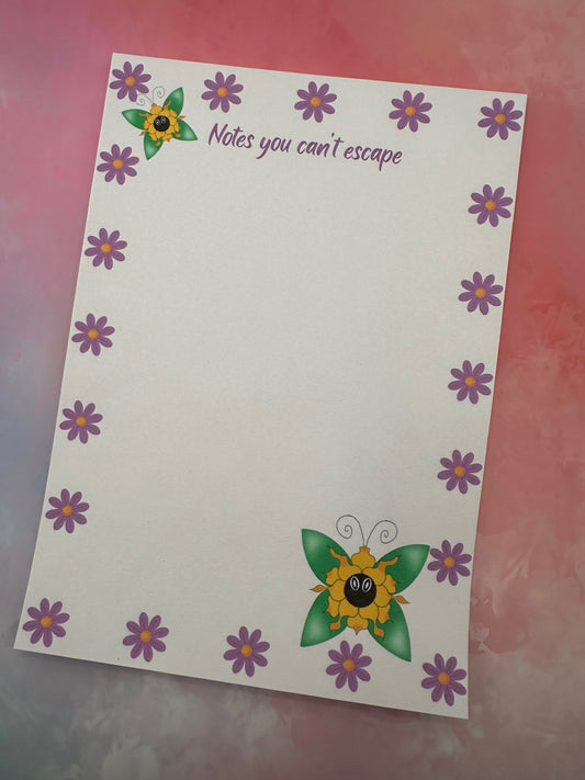 A notepad with fictional character that is a yellow flowery shape and has green wings coming from it. The notepad all around has purple flowers with a heading of "notes you can't escape". The notepad is sitting on top of a pink background.