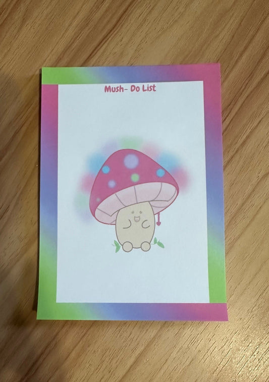 Notepad with heading "mush do list" with a cartoon mushroom design on a wooden surface. 