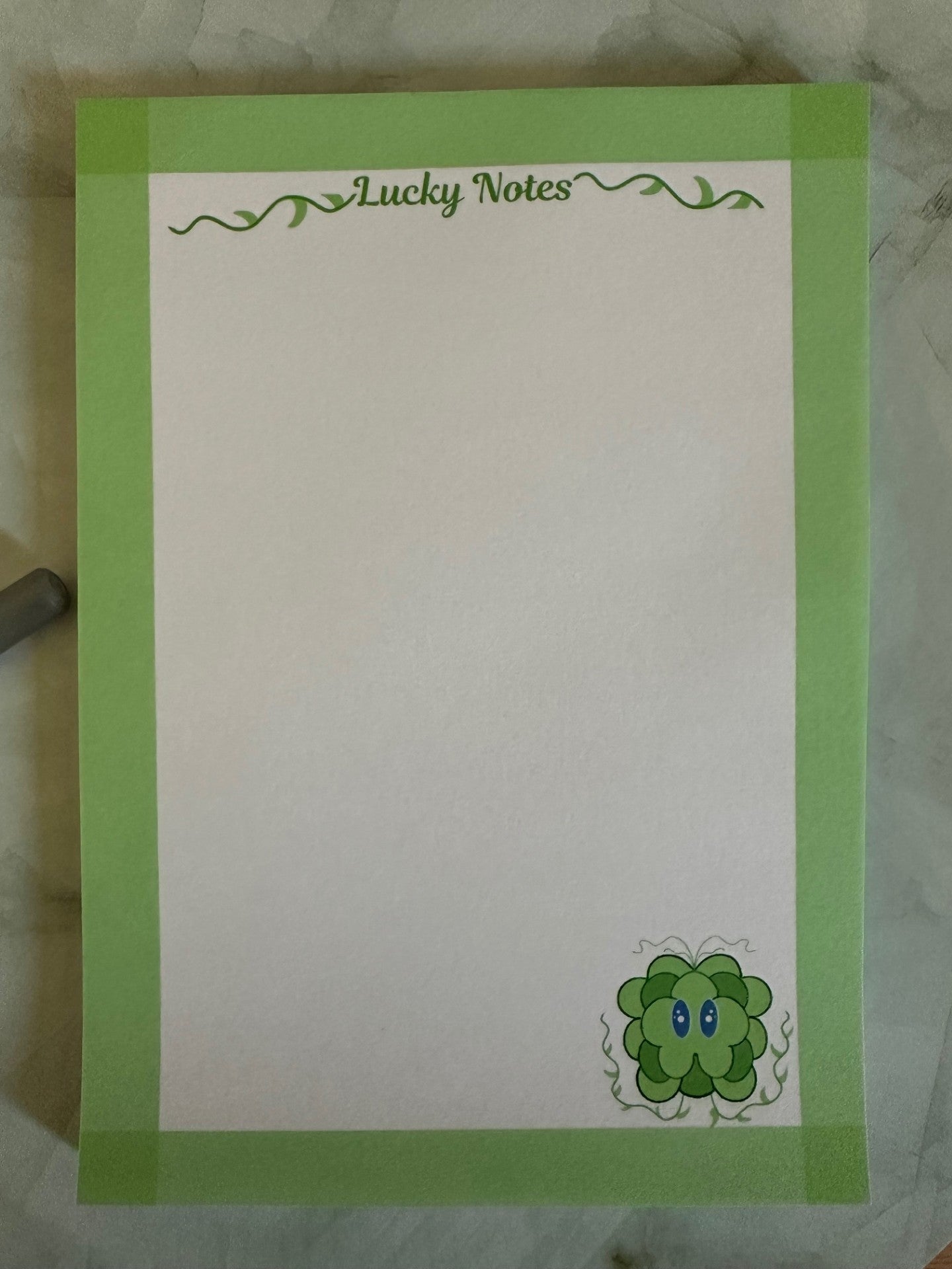 Note pad stating "lucky notes" on top. With fictional character lucky displayed on the bottom right. Lucky is a green and dark green color character with his vines up.