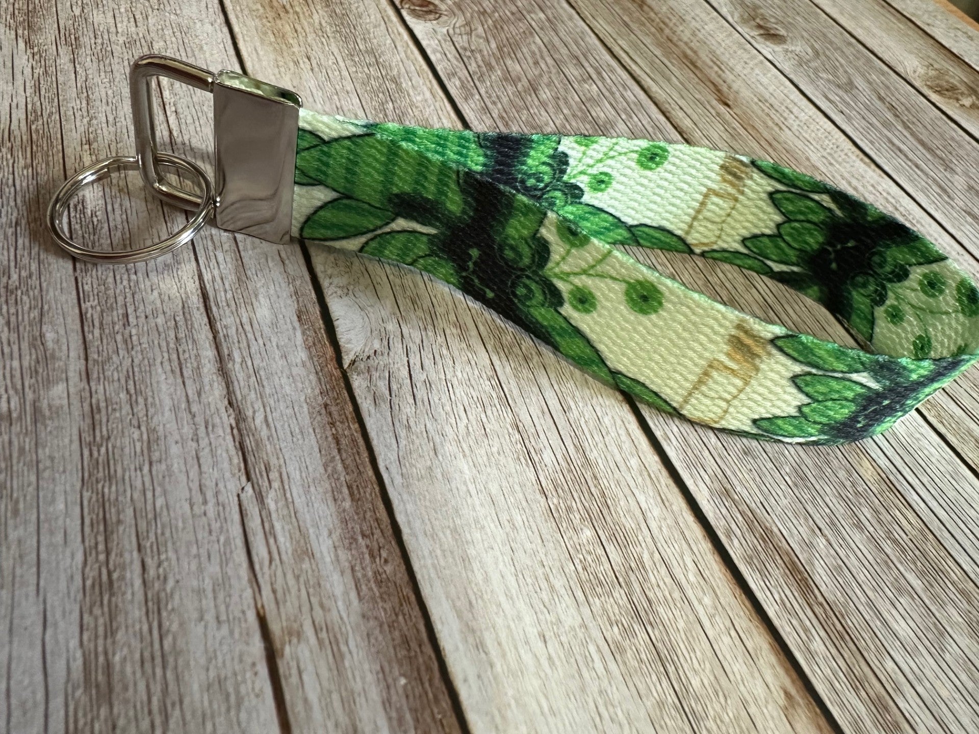 Green leaf-patterned character keychain on a wooden surface.