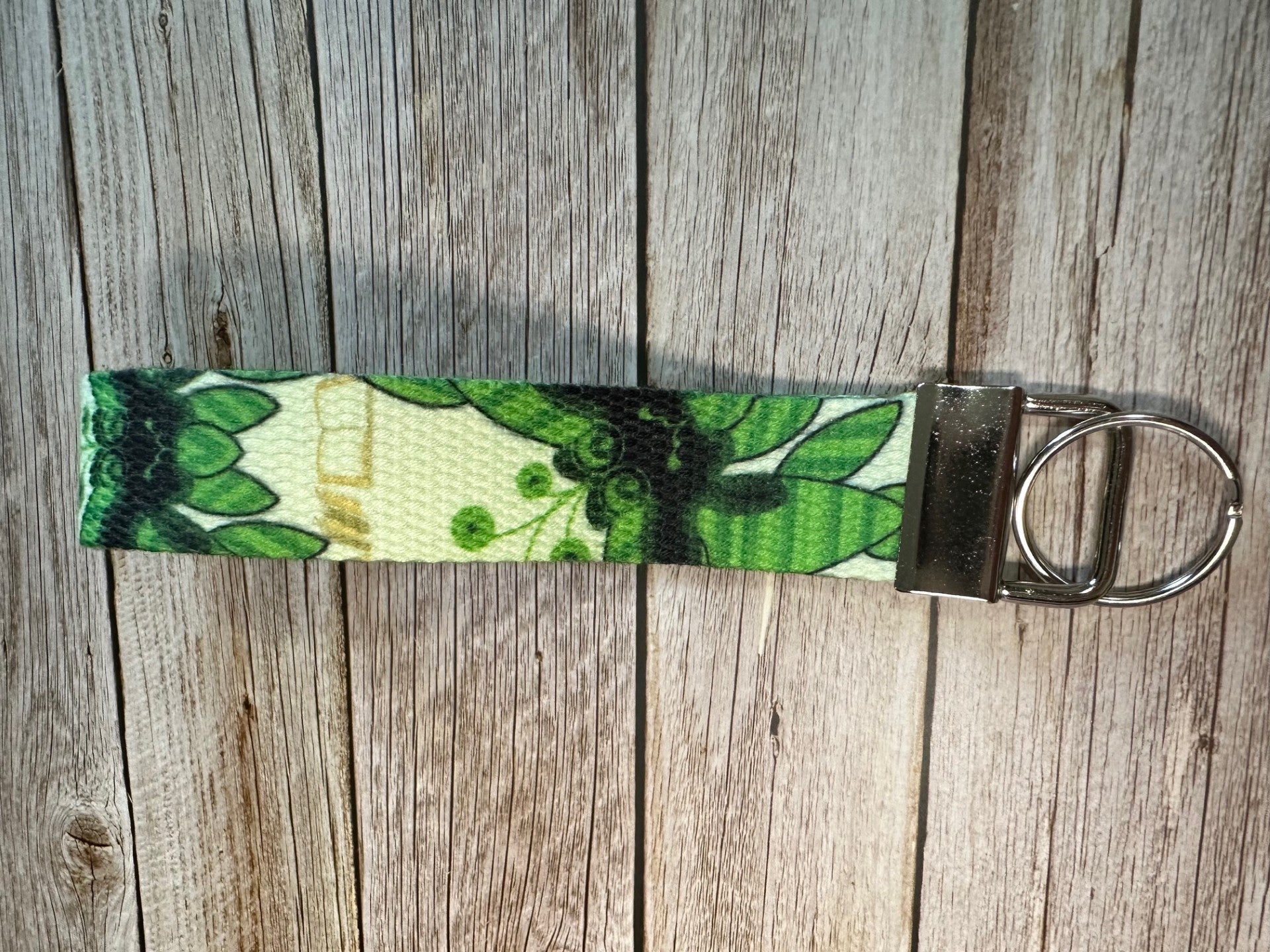 Keychain with green pattern character design on a wooden surface.