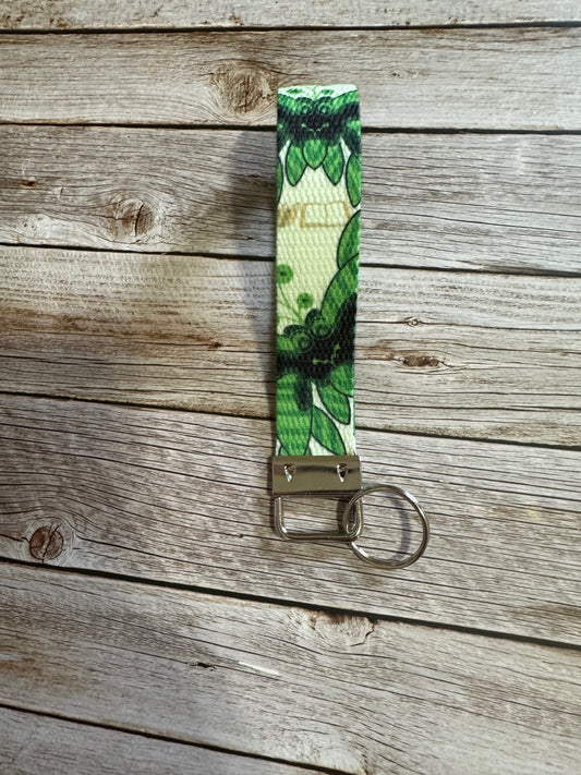Keychain with green leaf pattern on a wooden surface.