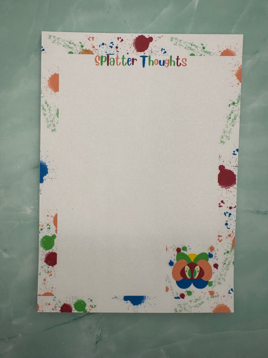 A notepad with a fictional character at the bottom of the notepad that is yellow, green, orange and blue color with green eyes. All around the notepad is different color splatters with a notepad heading of "Splatter thoughts". The notepad is sitting on a light green color background.  