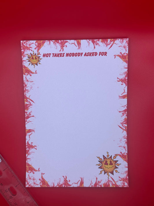 A notepad with character on top and bottom of notepad that looks like a sun with yellow and red colors and a smirk face. The notepad edges all around the corners have orange and red flames with the notepad heading of "Hot takes nobody asked for". The notepad is sitting on a red background next to a ruler. 
