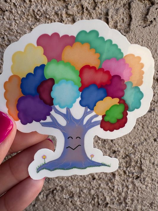Colorful tree-shaped sticker held by a hand on a textured surface.