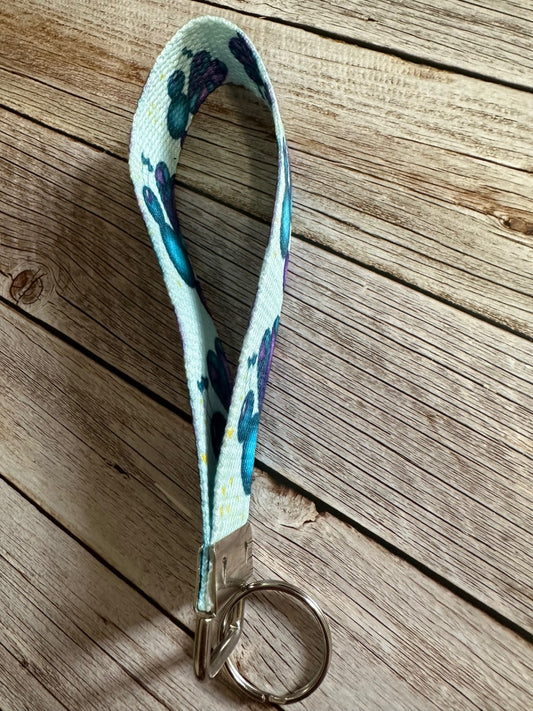 Keychain side view wristlet with fictional character love mist that is dark blue and purple sitting on a wooden surface.