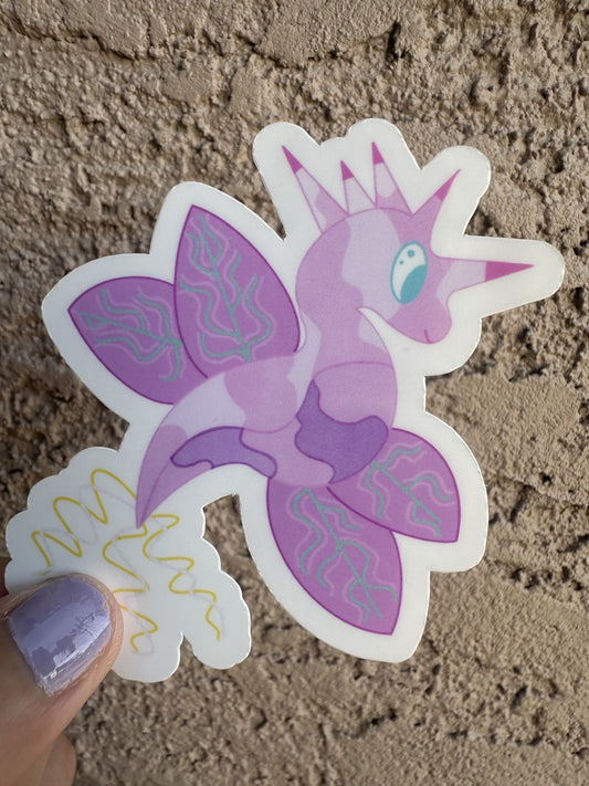 Fictional character sticker that is light purple and dark purple, that looks like a dragon and also has wings with turquoise lines. The character has five horns coming from its head that are pink and purple, while the tail is yellow and light pink. The character has light blue eyes. 
