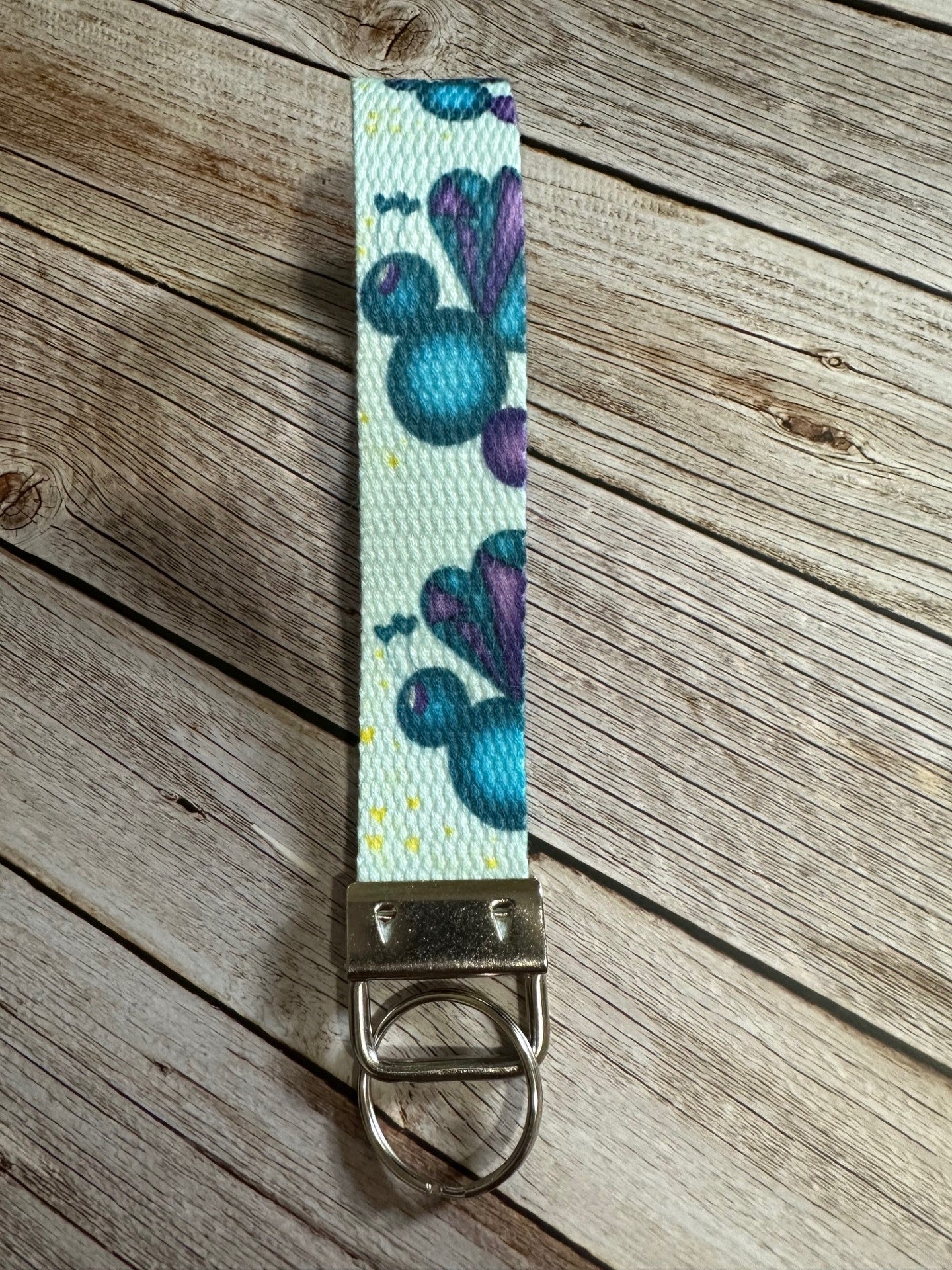 Keychain wristlet with fictional character love mist that is dark blue and purple sitting on a wooden surface.