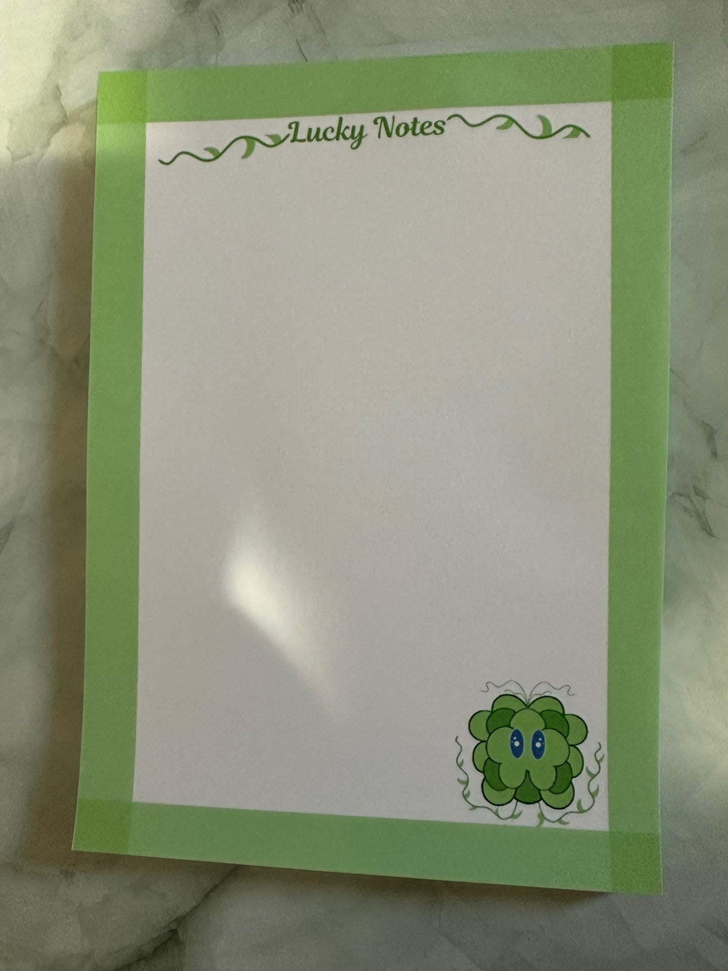 Note pad stating "lucky notes" on top. With fictional character lucky displayed on the bottom right. Lucky is a green and dark green color character with his vines up.