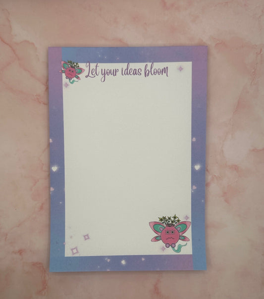 A notepad with fictional characters on top and bottom that are pink and turquoise color having yellow flowers come out of it. Around the notepad is purple color with hearts. The notepad heading states "let your ideas bloom". While the notepad is sitting on a pink background with a pen. 