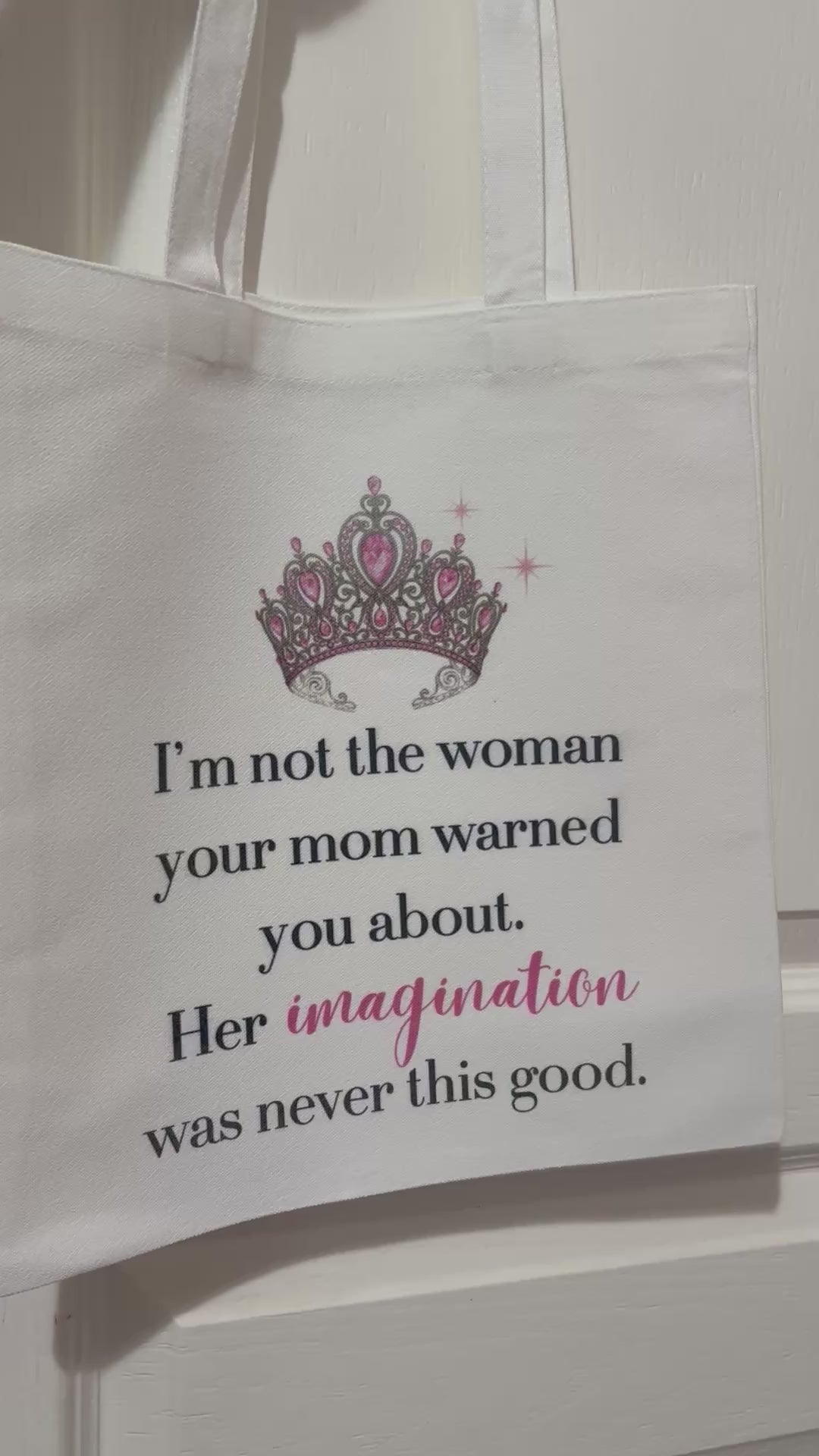 White tote bag featuring a pink and silver crown graphic and the quote: 'I'm not the woman your mom warned you about. Her imagination was never this good