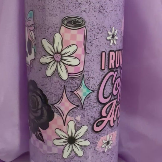 Purple snow globe tumbler with a black lid and straw, featuring the text: 'I RUN ON Coffee & Anxiety,' along with daisy and iced coffee illustrations.
