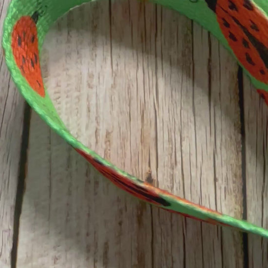 Video of the fabric wristlet keychain featuring a green background patterned with black and red ladybugs, shown on a light wooden surface.