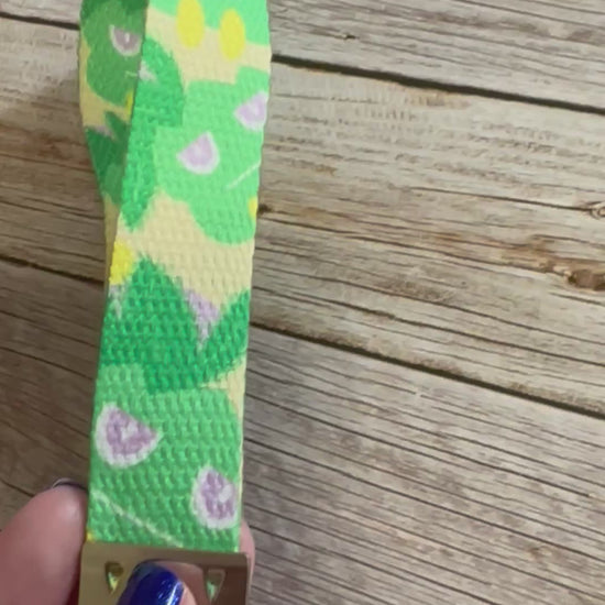 Keychain with a green and yellow pattern character on a wooden surface