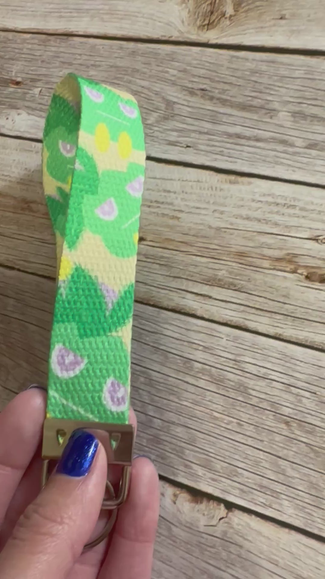 Keychain with a green and yellow pattern character on a wooden surface