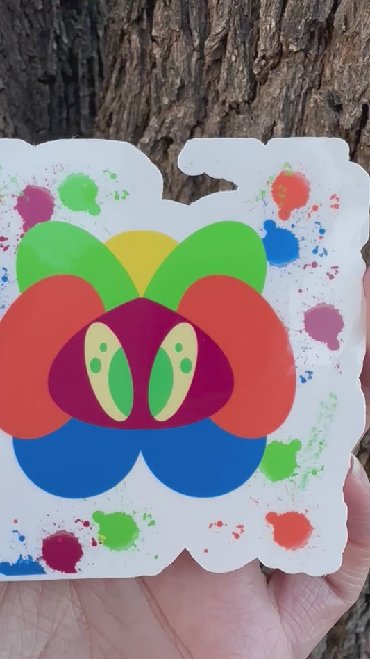 A sticker featuring an abstract, colorful creature made of layered organic shapes in orange, green, yellow, blue, red, and purple, surrounded by multi-colored paint splatters.