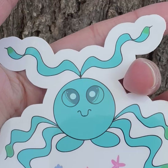 A sticker featuring a blue octopus sea like creature with long, wavy tentacles that have green tips, along with small illustrations of pink starfish and blue seashells.