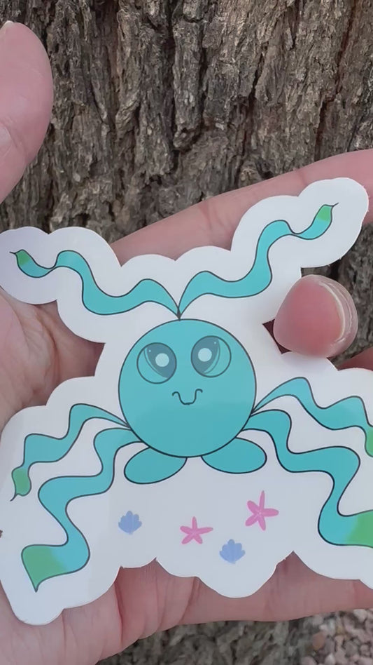 A sticker featuring a blue octopus sea like creature with long, wavy tentacles that have green tips, along with small illustrations of pink starfish and blue seashells.