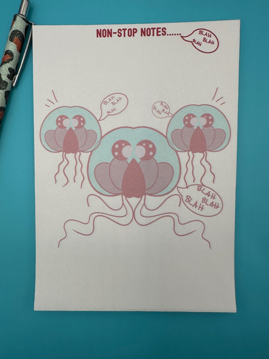 A notepad with three red jellyfish surrounded by the words "blah blah blah". The notepad heading has "non-stop notes.....". The notepad is sitting on a blue background with a pen.