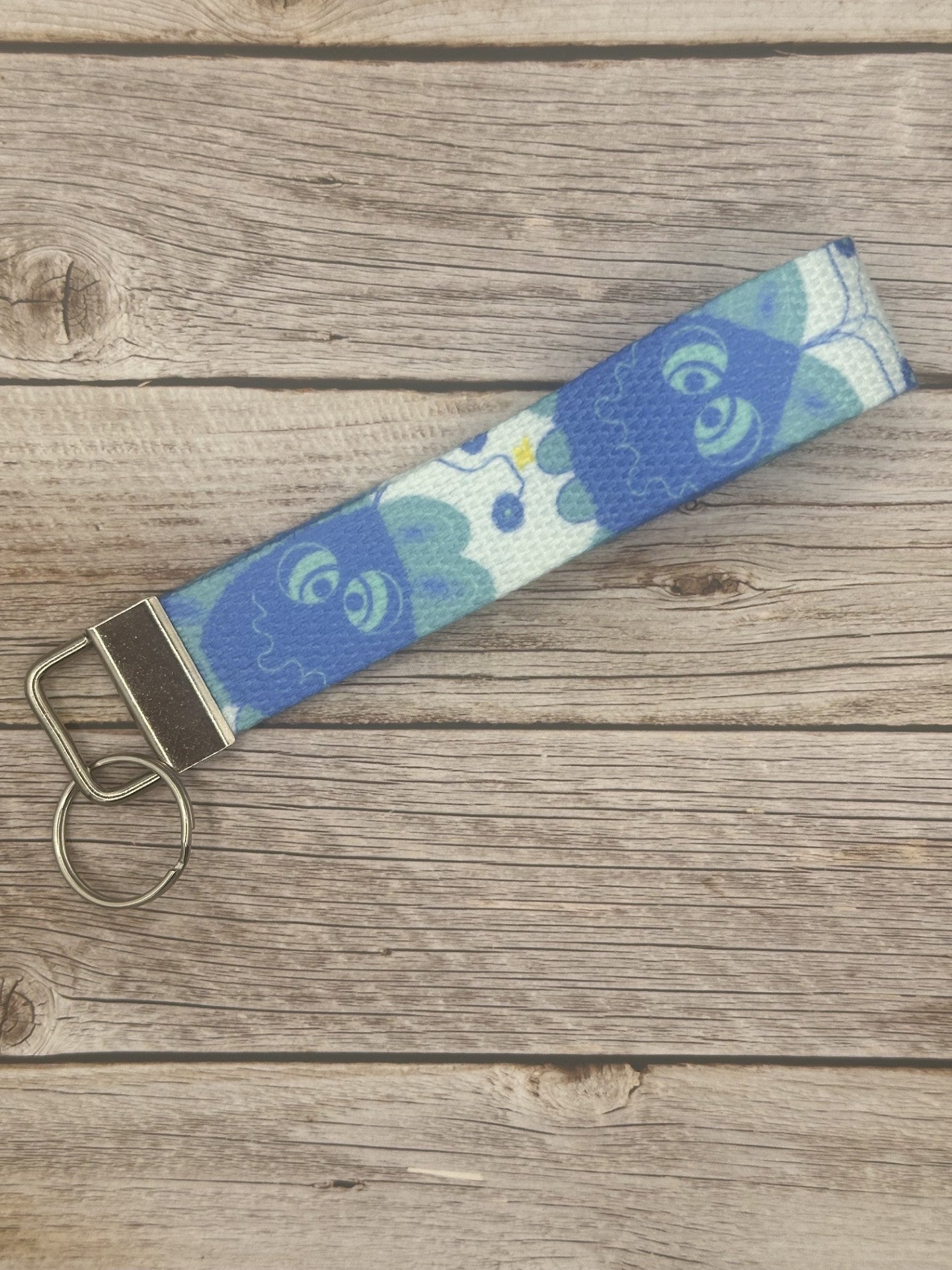 Blue unique character with turquoise eyes, and a little spark coming from it on a wooden surface.