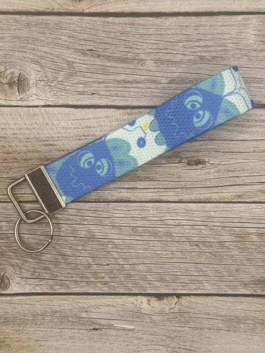 Blue unique character with turquoise eyes, and a little spark coming from it on a wooden surface.